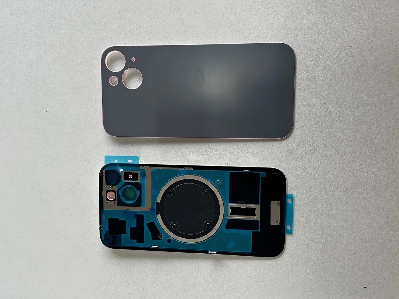 Tampa traseira e display de iPhone sobre a bancada da Cell Peças